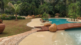 Opções de porcelanato para piscina e orientações de aplicação 5 Foto de uma piscina de areia que mostra como pode ser integrada na paisagem.